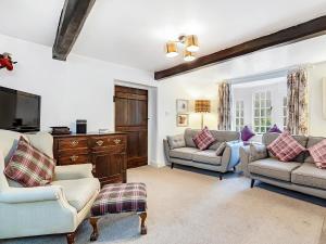 a living room with two couches and a tv at Wellside Cottage in Starbotton