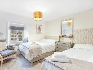1 dormitorio con 2 camas y 1 silla en Wellside Cottage, en Starbotton