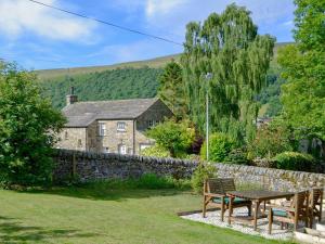 a table and chairs in front of a house at Wellside Cottage in Starbotton