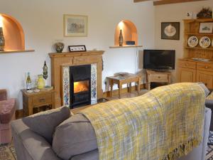 a living room with a couch and a fireplace at The Paddock in Saint Hilary