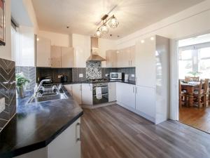 a large kitchen with white cabinets and a table at Dunmail House in Grange Over Sands