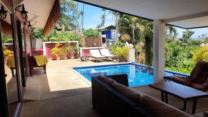 a patio with a pool and a couch and a table at Pink House Guest House Lamai - Pool & Sea View in Lamai