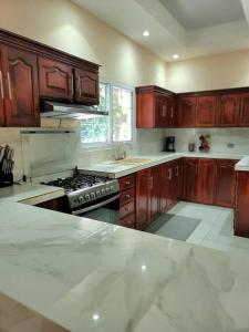 a kitchen with wooden cabinets and a stove top oven at Spacious & Spotless new house, 4 BRs in Roatan