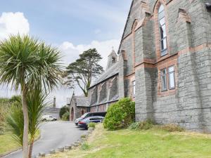an old stone building with a palm tree in front of it at White Sands in Criccieth