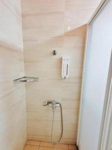 a bathroom with a shower with a phone on the wall at 綠竹弄親子民宿附設背包客房 in Ch'i-she
