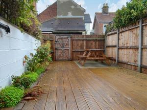 a wooden deck with a bench and a wooden fence at Scira in Sheringham