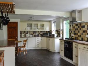 a kitchen with white cabinets and a table in it at Sunny Beck in High Nibthwaite