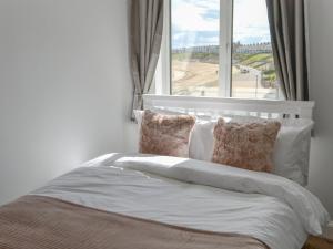 een slaapkamer met een bed en een groot raam bij Bertys Beach View in Woodhorn