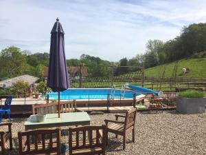a pool with a table and an umbrella and a playground at Outshot Barn in Dorstone