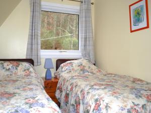 a bedroom with two beds and a window at Heather Lodge in Glenurguhart