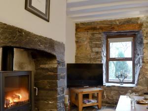 a living room with a stone fireplace and a television at Clawdd Gwyn in Llanrwst