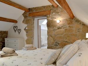 a bedroom with a stone wall and a bed at Clawdd Gwyn in Llanrwst