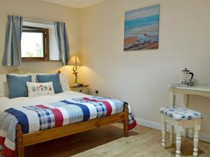 um quarto com uma cama, uma mesa e uma janela em Stonechat Barn em Pancrasweek