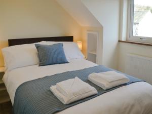 a bedroom with a bed with two towels on it at Crofters Cottage in Rothbury