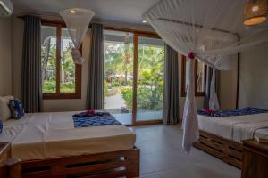 twee bedden in een kamer met een raam bij Michamvi Sunset Bay in Michamvi