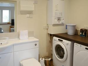 a bathroom with a washing machine and a sink at Crofters Cottage in Rothbury