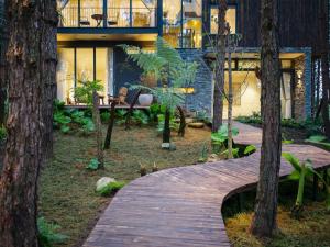 a wooden walkway in front of a house with trees at Mơ Stay - Forest Resort in Da Lat