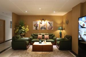 sala de estar con sofás verdes y TV en Lanura Apartments and Hotel en Ho Chi Minh