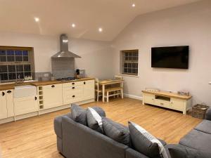 een woonkamer met een bank en een keuken bij Pointer Cottage in Preesall