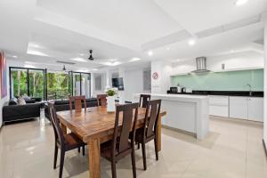 Il dispose d'une cuisine et d'un salon avec une table et des chaises en bois. dans l'établissement The Fairways Villas - 4 bedroom for 10 guests - 7kms to Patong beach, à Kathu