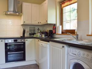 eine Küche mit weißen Schränken, einer Waschmaschine und einer Spüle in der Unterkunft Little Tigh Craggan - Uk10204 in Aberfeldy