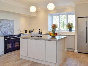 uma grande cozinha com armários brancos e uma bancada em Smithfield House em Tarbolton