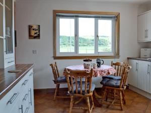 a kitchen with a table and chairs and a window at Ingleside in Ballantrae