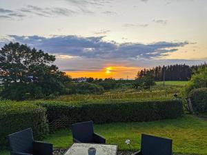 einen Sonnenuntergang über einem Garten mit Stühlen und einem Tisch in der Unterkunft Cuillin View Apartment - Uk12529 in Arisaig