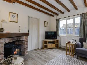 a living room with a fireplace and a tv at The Old Saddlery in Colkirk