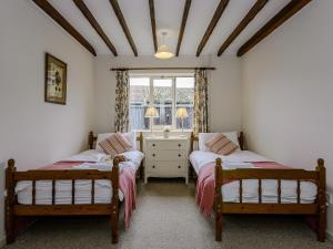 a bedroom with two beds and a window at The Old Saddlery in Colkirk