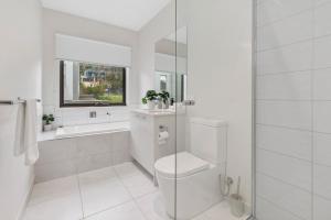 a white bathroom with a toilet and a shower at Boardwalk Villa in Safety Beach +12 photos