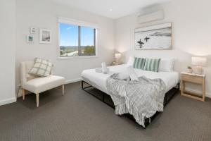 a bedroom with a large white bed and a chair at Boardwalk Villa in Safety Beach