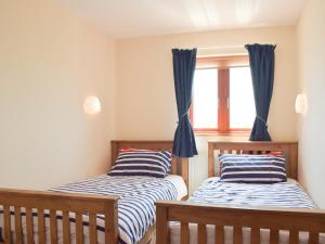 two beds in a room with a window at Marina Retreat in Milford Haven