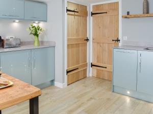 cocina con armarios blancos y suelo de madera en The Old Toll House, en Portpatrick