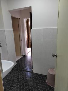 een badkamer met een wit bad en een zwarte tegelvloer bij Nilai Impian Homestay @ Dillenia in Nilai