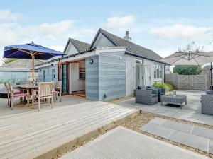 a blue house with a deck with a table and chairs at Beach Holme in East Wittering