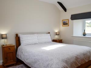 a bedroom with a white bed and a window at Stanegate Cottage in Greenhead
