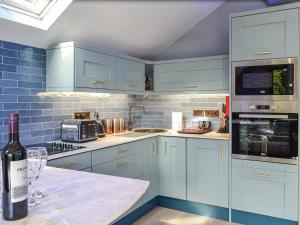una cocina azul con una botella de vino en la barra en Dundonald Landing - Palm 3 - Uk35430, en Connel