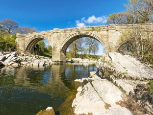 a stone bridge over a river with rocks at The Nook in Kirkby Lonsdale