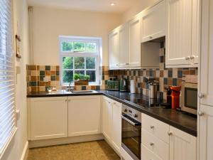 a kitchen with white cabinets and a window at Daisy Cottage in Sea Palling