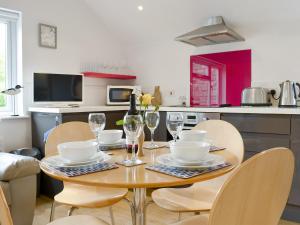 a kitchen with a table and chairs with wine glasses at Purbeck Apartment in Chideock