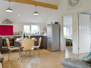 uma cozinha e sala de estar com mesa e cadeiras em Purbeck Apartment em Chideock