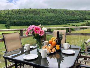 una mesa con un jarrón de flores y una botella de vino en Offas Dyke Lodge - Uk10835, en Old Radnor