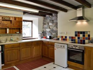 a kitchen with wooden cabinets and a white dishwasher at Valley Cottage in Penmachno