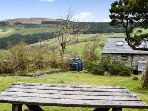 a wooden bench sitting on top of a field at Valley Cottage in Penmachno