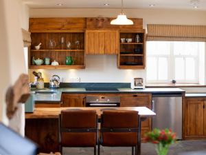 cocina con armarios de madera y lavavajillas de acero inoxidable en Gowan Bank Farm Cottage, en Staveley