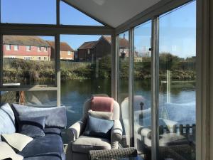 a screened in porch with two chairs and windows at Waters Edge Holiday Home in Beadnell