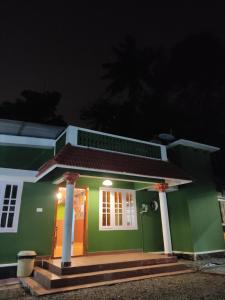 una casa verde y blanca por la noche en Lovely Home Stay Munnar en Munnar