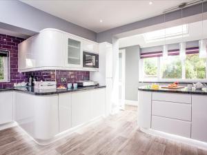 a kitchen with white cabinets and purple walls at Devon Sands in Paignton