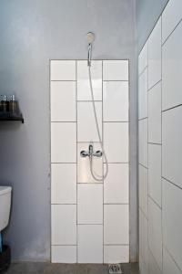 łazienka z prysznicem wyłożona białymi kafelkami. w obiekcie Ambara U6 Loft by Hombali w mieście Canggu